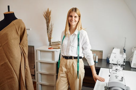 Cheerful seamstress poses at her workplace 